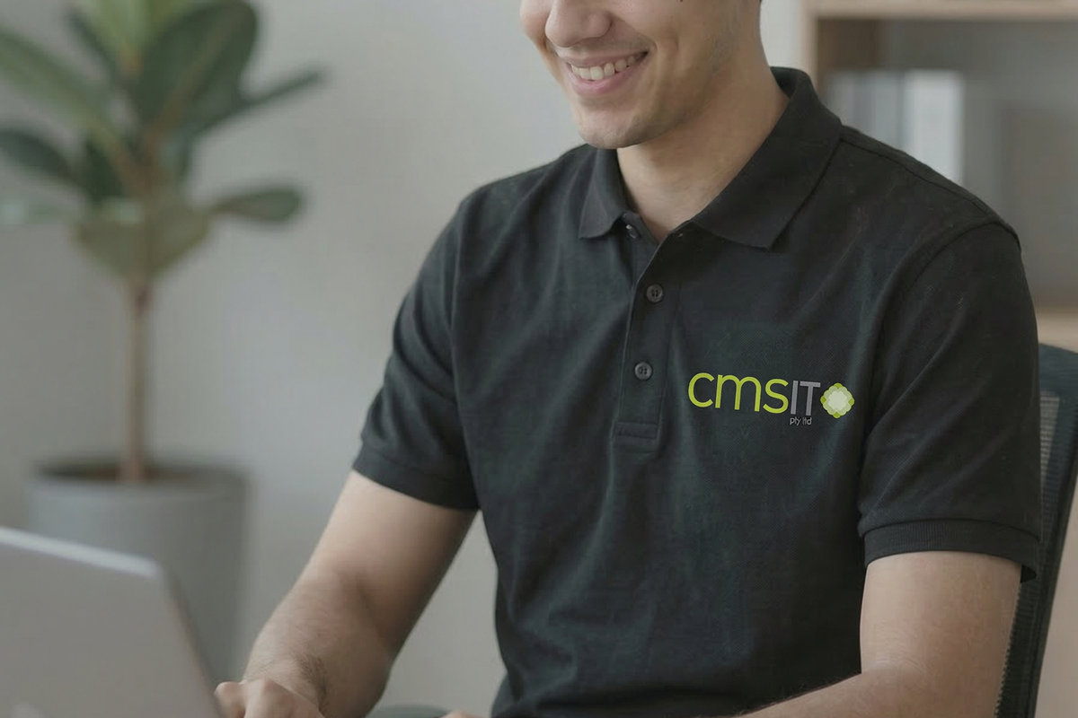CMS IT engineer in a branded shirt working at a laptop